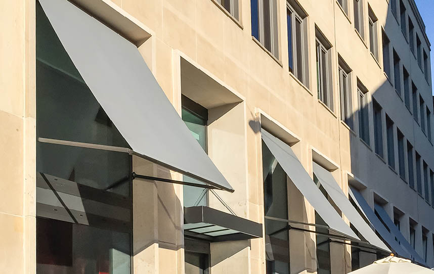 Hausfassade mit mehreren ausgefahrenen Markisen an einem sonnigen Tag