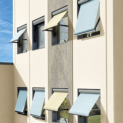 Hausfassade mit mehreren ausgefahrenen Markisen an einem sonnigen Tag