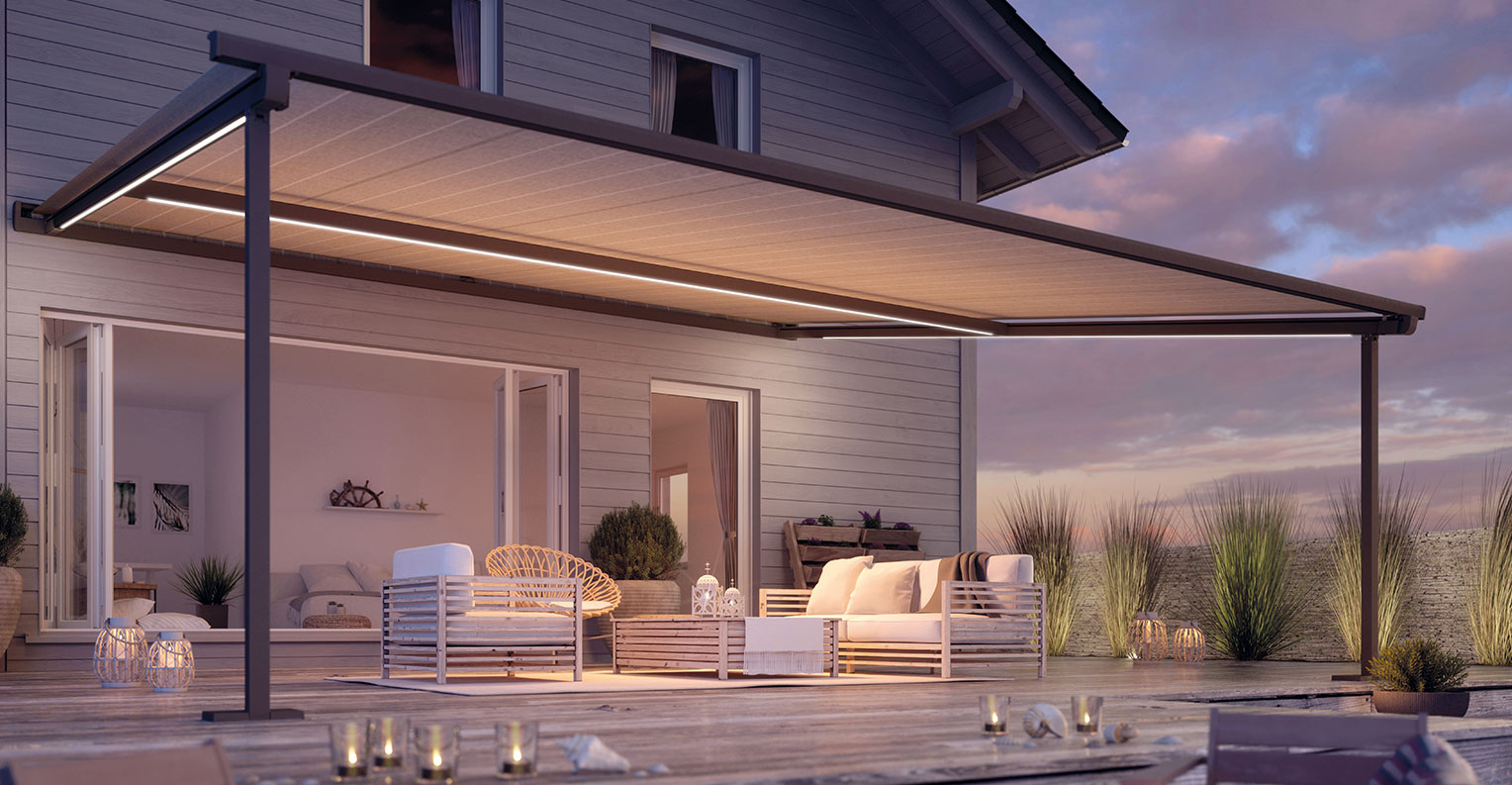 Moderne Terrasse bei Dämmerung mit beleuchteter Pergola-Markise und gemütlichem Sitzbereich