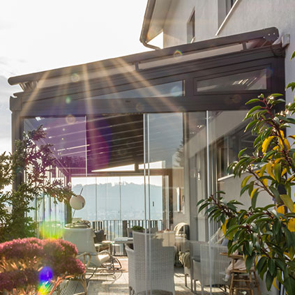 Abgeschrägte Glasdachmarkise auf einem Glasdach mit Vollverglasung an einer Hausfassade
