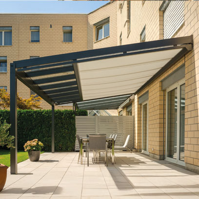 Glasdach an einer Hausfassade über einer Terrasse mit Unterglasmarkise