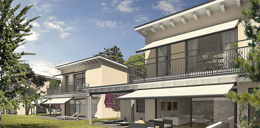 Mehrstöckiges Wohnhaus mit Balkonen und ausgefahrenen Markisen an sonnigem Tag