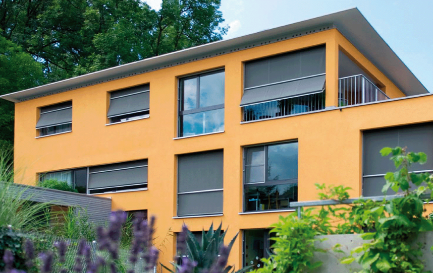 Orangenes Haus mit Fenstern und Ausstellmarkisen