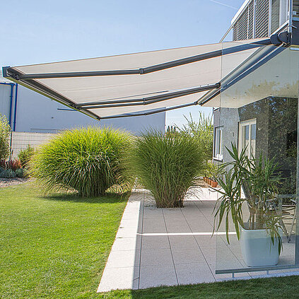Seitliche Ansicht einer Markise an einem Haus mit Terrasse und Garten