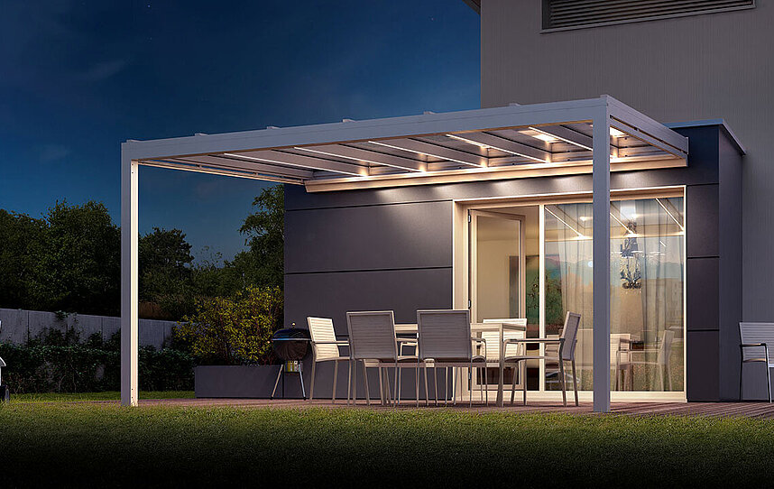 Glasdach bei Nacht mit Licht an einem Haus mit Terrasse und Garten