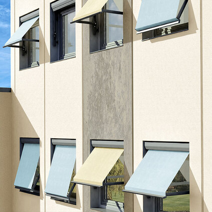 Hausfassade mit mehreren ausgefahrenen Markisen an einem sonnigen Tag